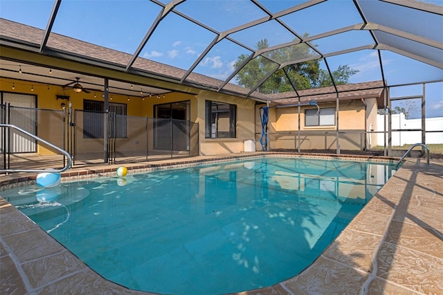 view of pool featuring glass enclosure, ceiling fan, and a patio area