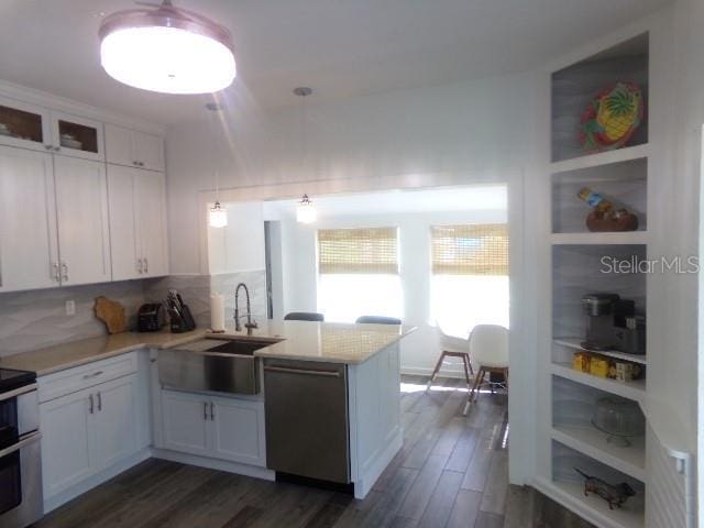 kitchen with a peninsula, white cabinetry, light countertops, stainless steel dishwasher, and range