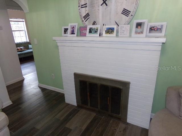 interior details with arched walkways, a fireplace, wood finished floors, and baseboards