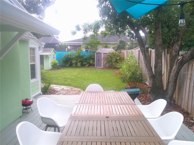 view of patio / terrace featuring outdoor dining space, a fenced backyard, an outbuilding, and a storage shed