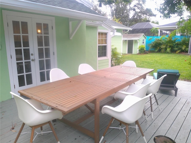 deck featuring a storage shed, a lawn, an outbuilding, french doors, and outdoor dining space