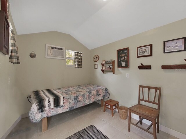 bedroom featuring light tile patterned floors, baseboards, vaulted ceiling, and a wall mounted AC