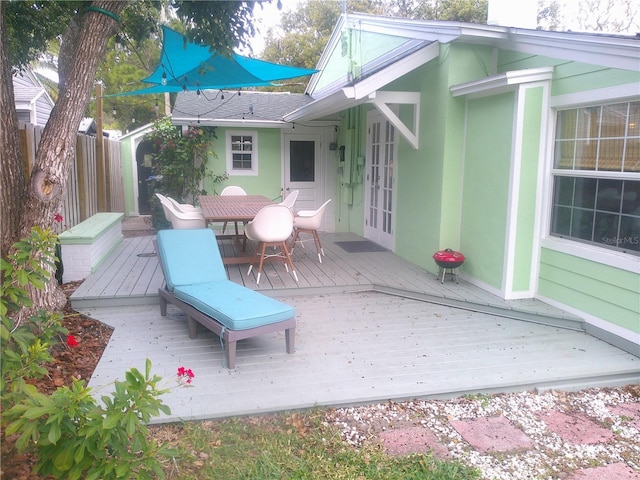 deck with french doors, outdoor dining area, and fence