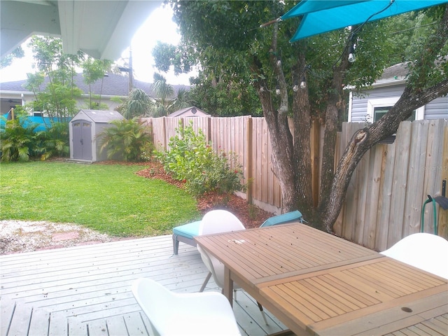 deck featuring outdoor dining area, a lawn, a shed, a fenced backyard, and an outdoor structure