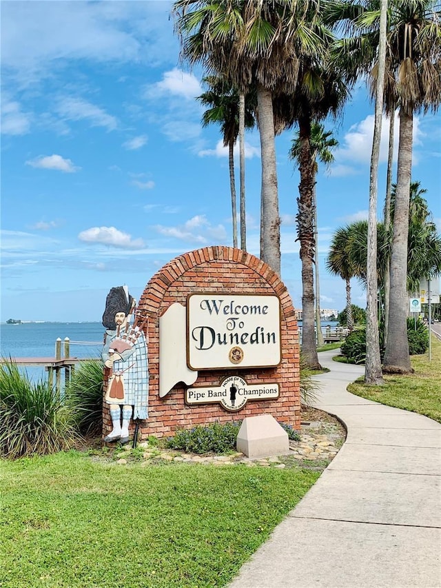 community sign with a water view and a lawn