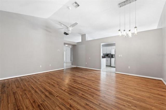 unfurnished living room featuring hardwood / wood-style floors, vaulted ceiling, and ceiling fan