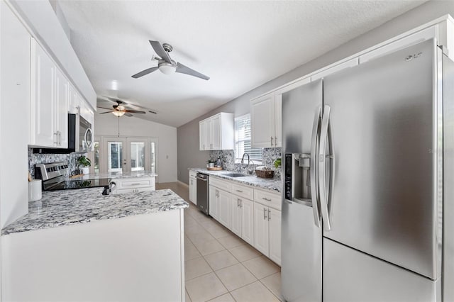 kitchen featuring white cabinets, appliances with stainless steel finishes, backsplash, and vaulted ceiling