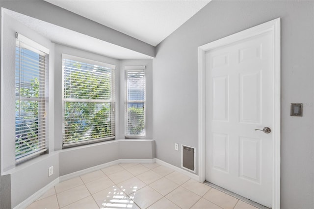 tiled empty room with lofted ceiling