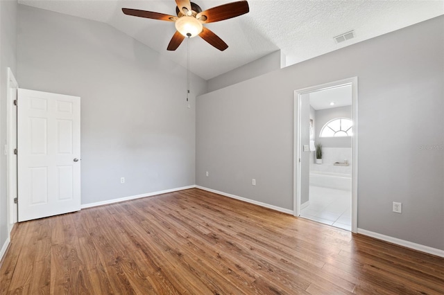 unfurnished bedroom with hardwood / wood-style flooring, ceiling fan, vaulted ceiling, and ensuite bath