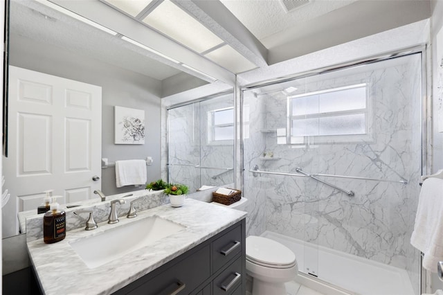 bathroom featuring vanity, a textured ceiling, a shower with door, tile patterned flooring, and toilet