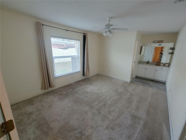 carpeted spare room featuring ceiling fan and sink