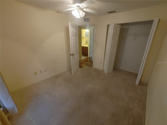 unfurnished bedroom featuring a closet, ceiling fan, and light colored carpet