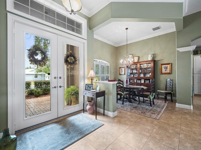 tiled entrance foyer with a notable chandelier, crown molding, and french doors