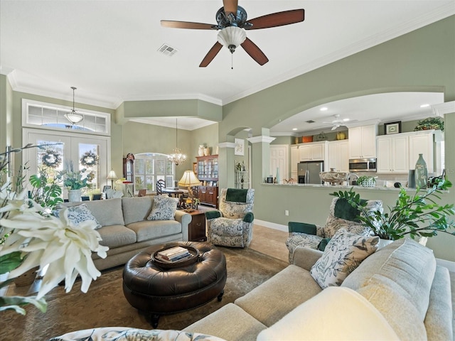 living room featuring ceiling fan with notable chandelier, ornamental molding, and french doors