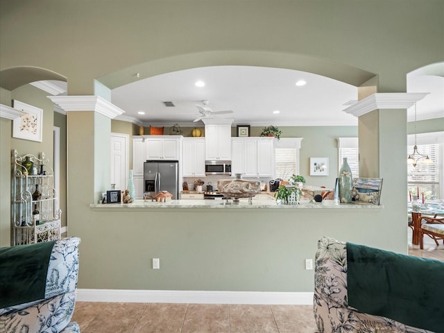 kitchen featuring kitchen peninsula, appliances with stainless steel finishes, white cabinetry, and crown molding