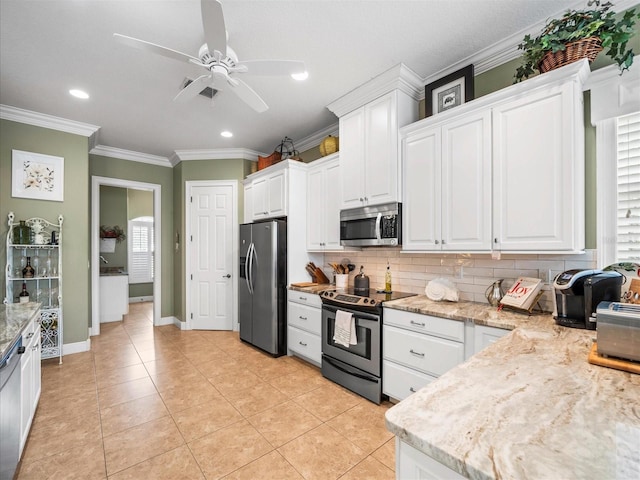 kitchen featuring white cabinets, light tile patterned floors, stainless steel appliances, and ornamental molding