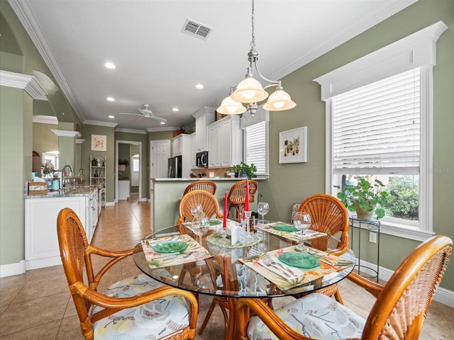 tiled dining area with ceiling fan and ornamental molding