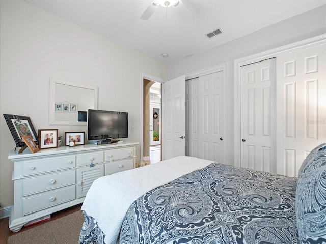 bedroom featuring ceiling fan, dark wood-type flooring, and multiple closets