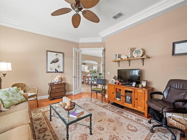 living room with ceiling fan, light wood-type flooring, crown molding, and french doors