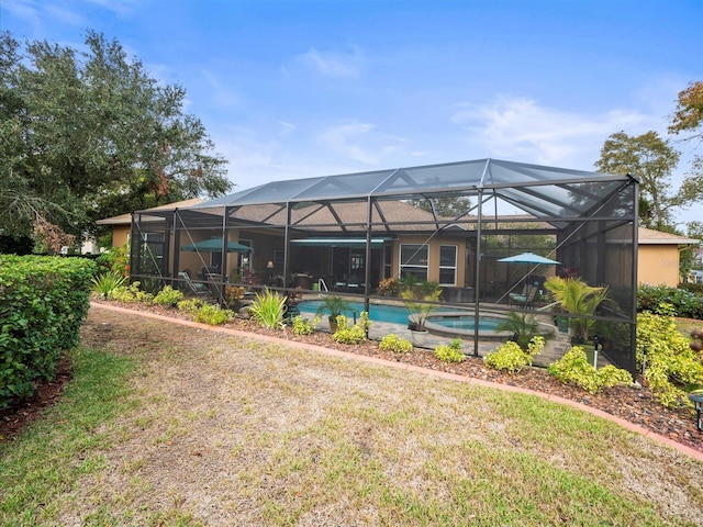 back of property featuring a swimming pool with hot tub and glass enclosure