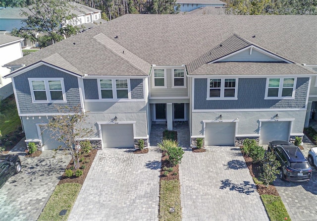 view of front of house featuring an attached garage, a shingled roof, decorative driveway, and stucco siding