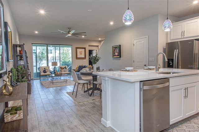 kitchen with pendant lighting, white cabinets, ceiling fan, an island with sink, and appliances with stainless steel finishes