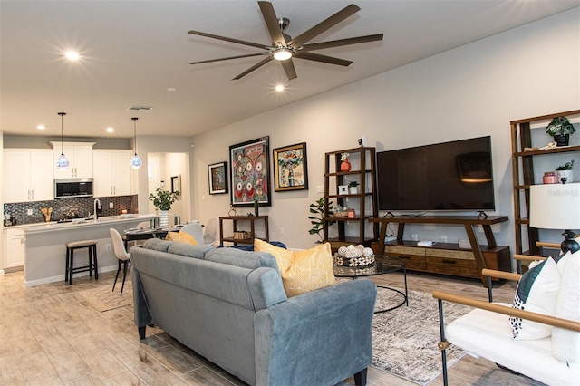 living room featuring ceiling fan, light hardwood / wood-style floors, and sink