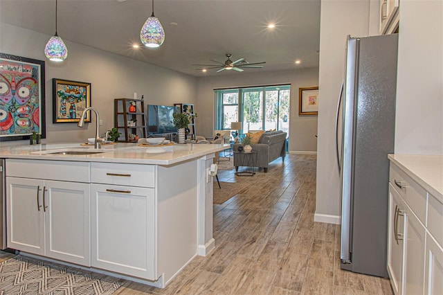 kitchen with white cabinets, hanging light fixtures, sink, ceiling fan, and stainless steel refrigerator