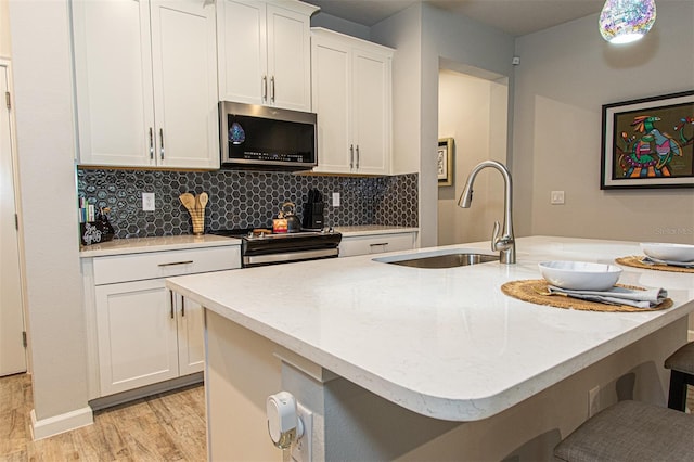 kitchen featuring a center island with sink, sink, light hardwood / wood-style flooring, appliances with stainless steel finishes, and white cabinetry