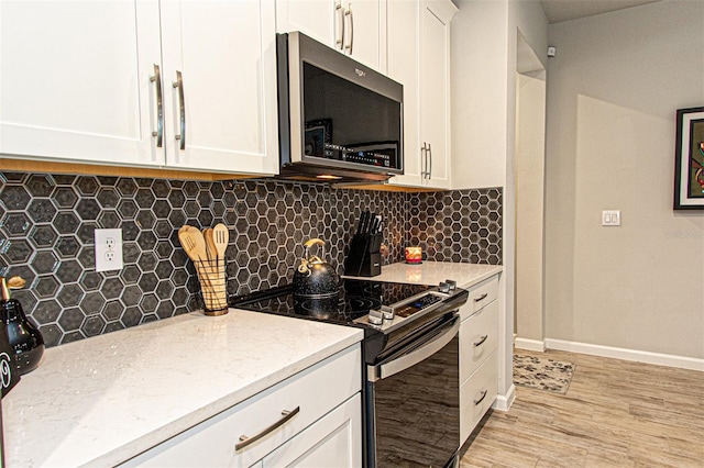 kitchen with white cabinets, stainless steel appliances, light stone counters, and tasteful backsplash