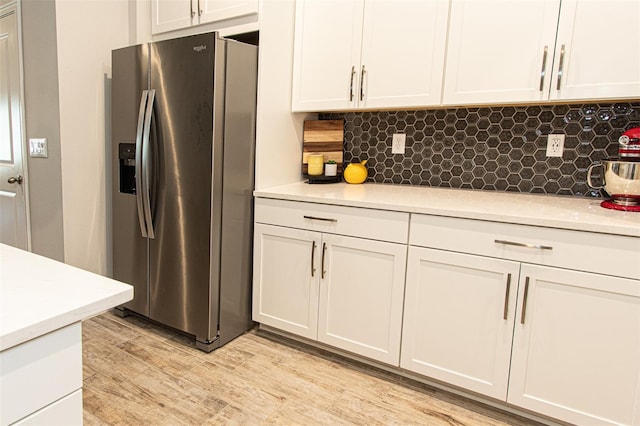 kitchen featuring white cabinetry, backsplash, stainless steel fridge with ice dispenser, and light wood-type flooring