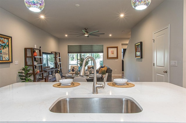 kitchen with light stone countertops, sink, and ceiling fan