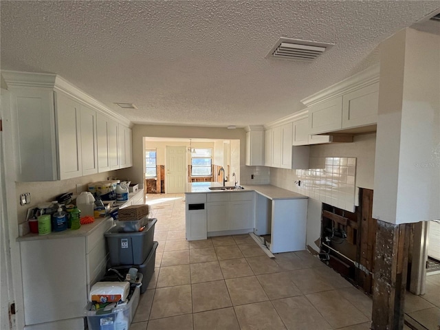 kitchen featuring white cabinetry, sink, light tile patterned floors, and a textured ceiling