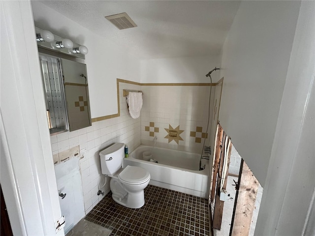 bathroom with a textured ceiling, toilet, tile walls, and shower / tub combo with curtain