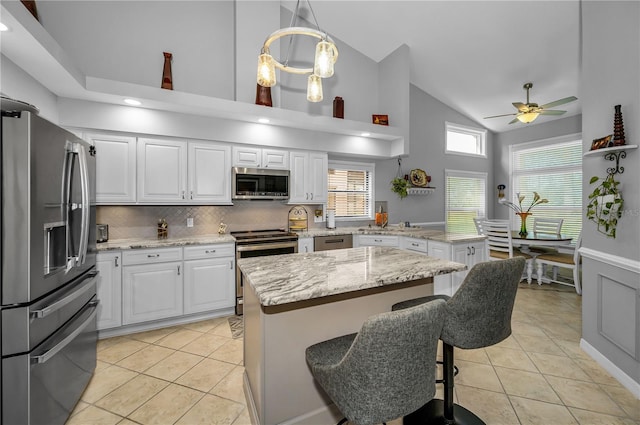 kitchen with white cabinetry, decorative light fixtures, stainless steel appliances, light stone countertops, and decorative backsplash