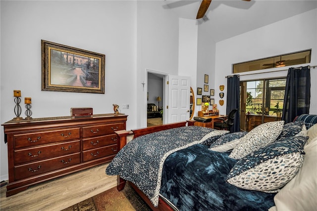 bedroom featuring a towering ceiling, access to outside, ceiling fan, and light hardwood / wood-style flooring