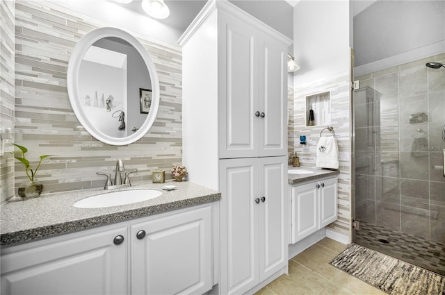 bathroom with tile patterned floors, a shower with shower door, tile walls, vanity, and decorative backsplash