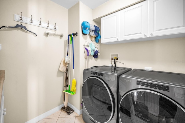 laundry room featuring cabinets, light tile patterned floors, and washing machine and clothes dryer