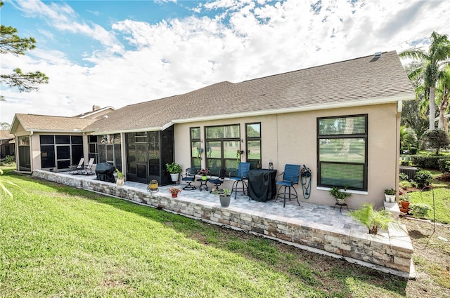 rear view of property featuring a sunroom, a lawn, and a patio area