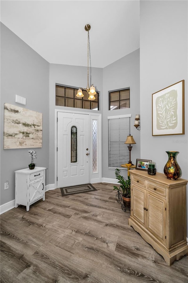 entryway with vaulted ceiling, hardwood / wood-style floors, and a notable chandelier