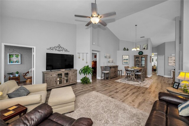 living room featuring ceiling fan, high vaulted ceiling, and light hardwood / wood-style flooring