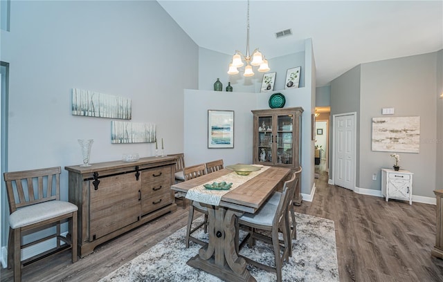 dining room with an inviting chandelier, hardwood / wood-style floors, and high vaulted ceiling