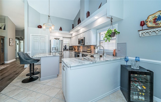 kitchen featuring wine cooler, sink, a kitchen breakfast bar, kitchen peninsula, and stainless steel appliances