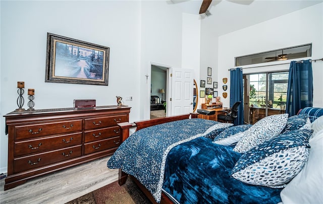 bedroom featuring hardwood / wood-style floors, a towering ceiling, access to outside, and ceiling fan