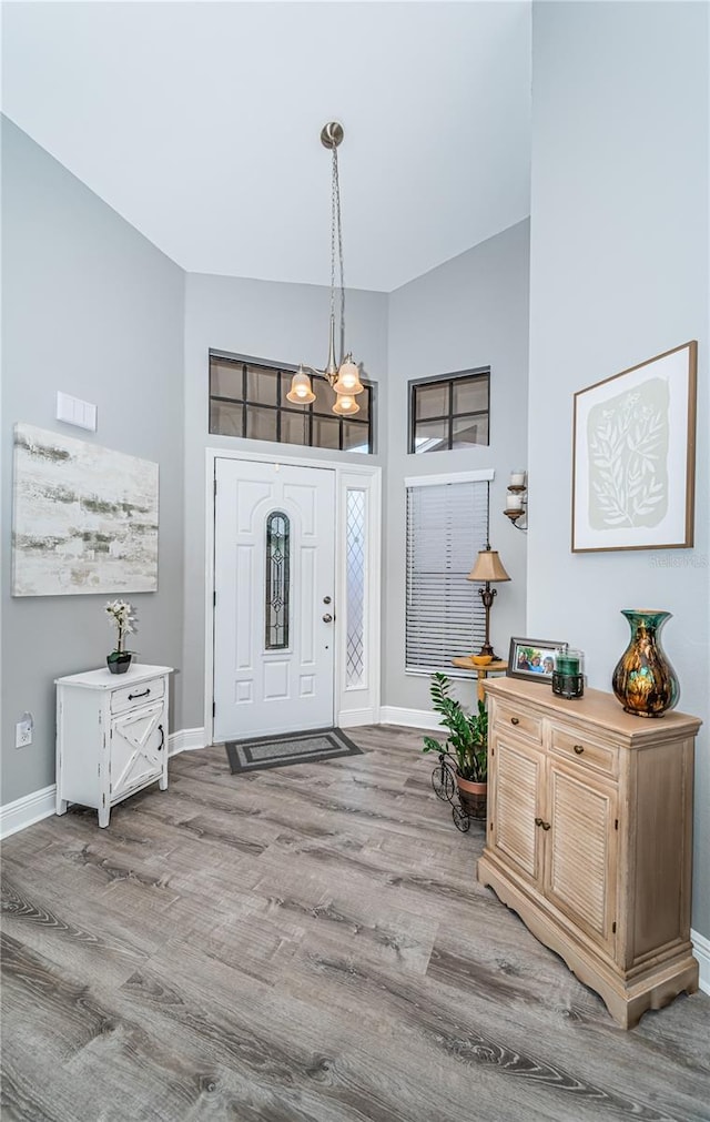 foyer entrance with a towering ceiling, light hardwood / wood-style flooring, and a chandelier