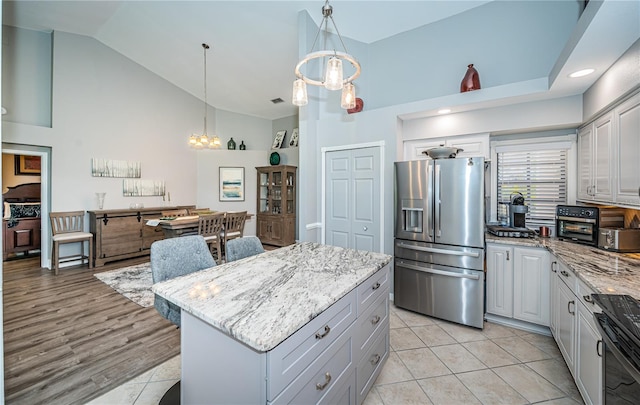 kitchen featuring pendant lighting, stainless steel fridge, stove, a kitchen island, and a chandelier