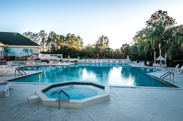 view of swimming pool featuring a hot tub and a patio area