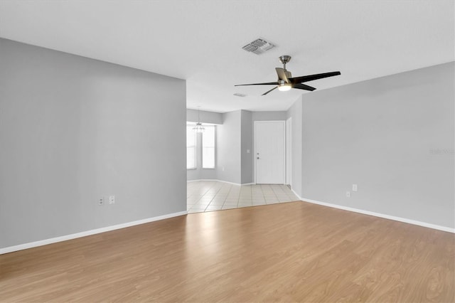 empty room with ceiling fan with notable chandelier and light hardwood / wood-style floors