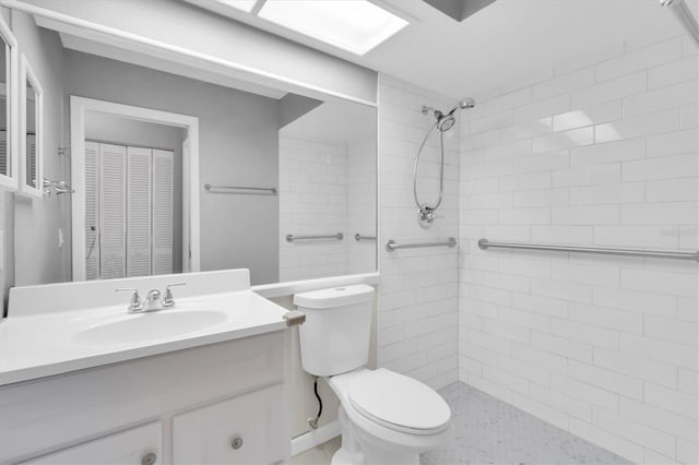 bathroom featuring a tile shower, vanity, and toilet