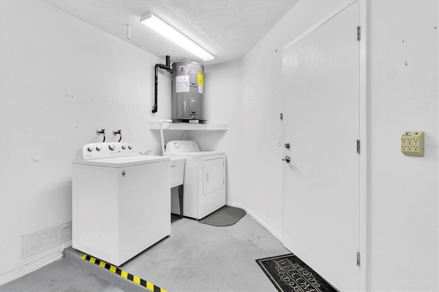 laundry room featuring washing machine and clothes dryer, electric water heater, and a textured ceiling